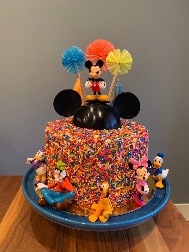 Sprinkle cake with black mickey mouse hat and mickey and friends figurines